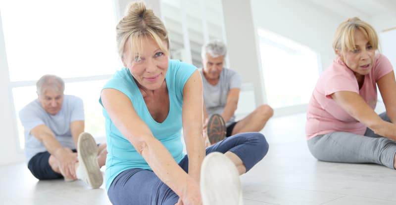 Middle-aged woman stretching legs in exercise class