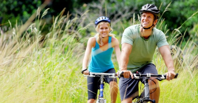 Active young couple biking outdoors helps keep veins healthy