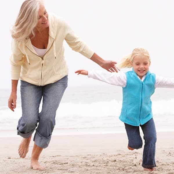 Grandmother in jeans on beach with granddaughter