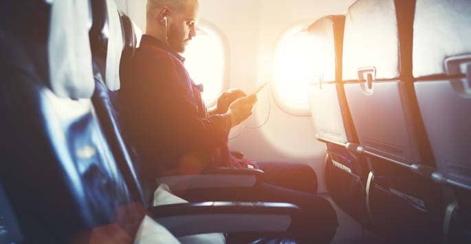 Man in airplane window seat checking his phone