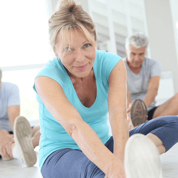 Middle-aged woman stretching legs in exercise class