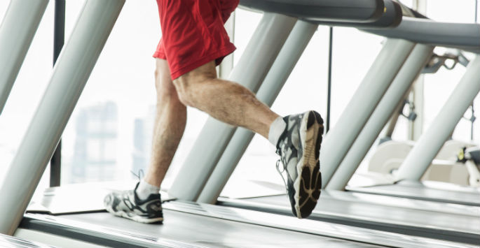 Man's legs running on treadmill overlooking a city view